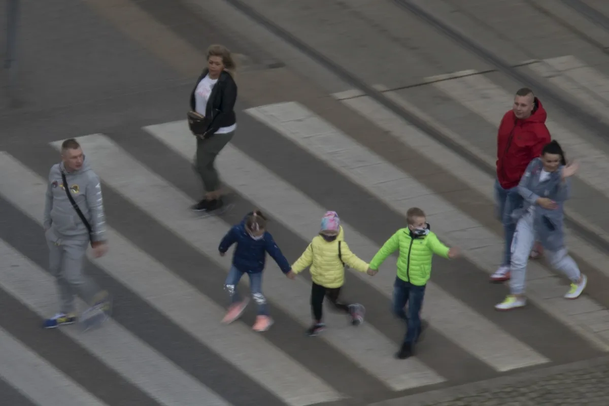 Group of children in bright green jackets crossing a street